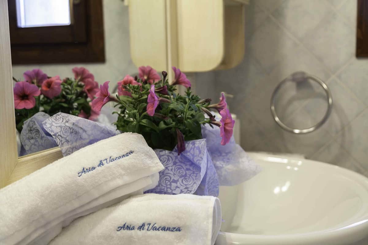 Ein Badezimmer mit Waschbecken, Spiegel und Handtüchern mit der Aufschrift "Aqua di Vacanza".