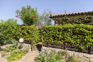 A garden with a stone wall, a wooden fence, and a lamp post. - Aria di Vacanza - S'Abba Lughente (Olbia)