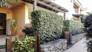 A building with a stone wall, wooden fence, and a paved pathway. - Aria di Vacanza - S'Abba Lughente (Olbia)