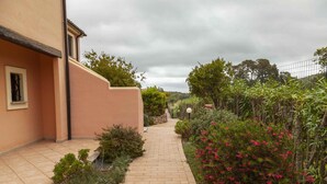 A paved pathway leading to a building with a beige exterior. - Aria di Vacanza - S'Abba Lughente (Olbia)