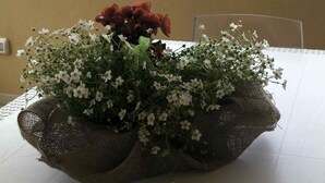 Una mesa con un arreglo floral de arpillera y una rosa roja, con vistas a un paisaje montañoso.