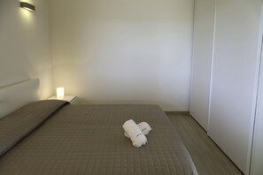 Un lit bien fait, recouvert d’une courtepointe matelassée, avec deux serviettes pliées posées sur le lit.