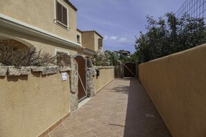 Un étroit sentier mène à un bâtiment doté d’un mur en pierre et d’une porte en métal.