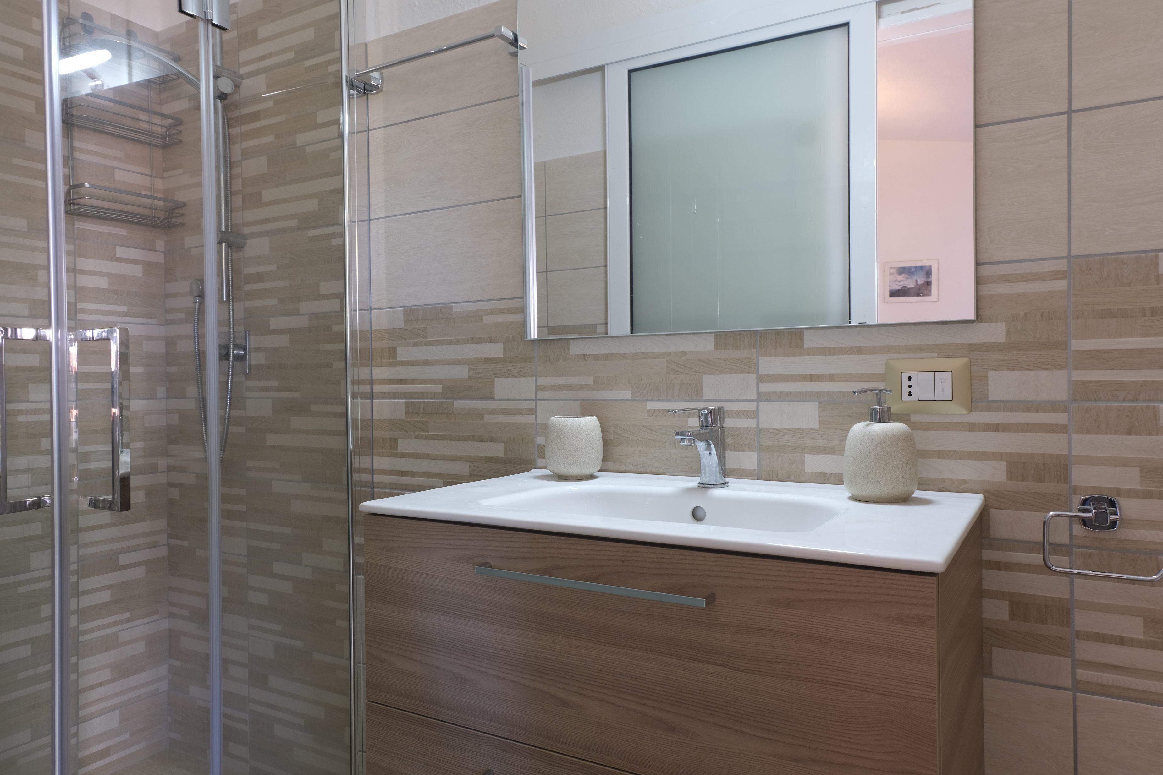Ein modernes Badezimmer mit Duschkabine aus Glas, einem Holztischchen mit Waschbecken und einem großen Spiegel darüber.