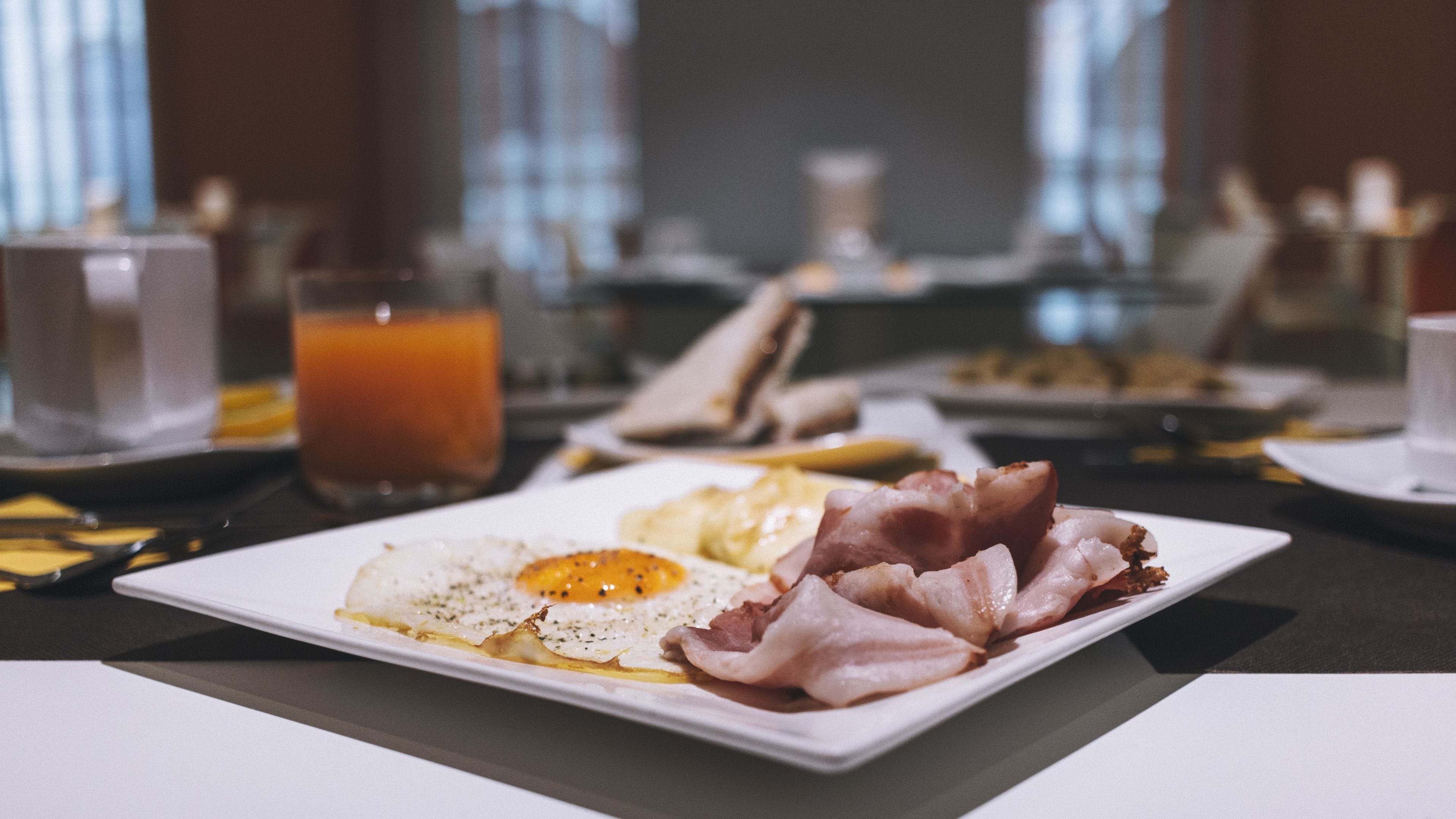 Un plato de desayuno con huevos, tocino y tostadas sobre un plato blanco.