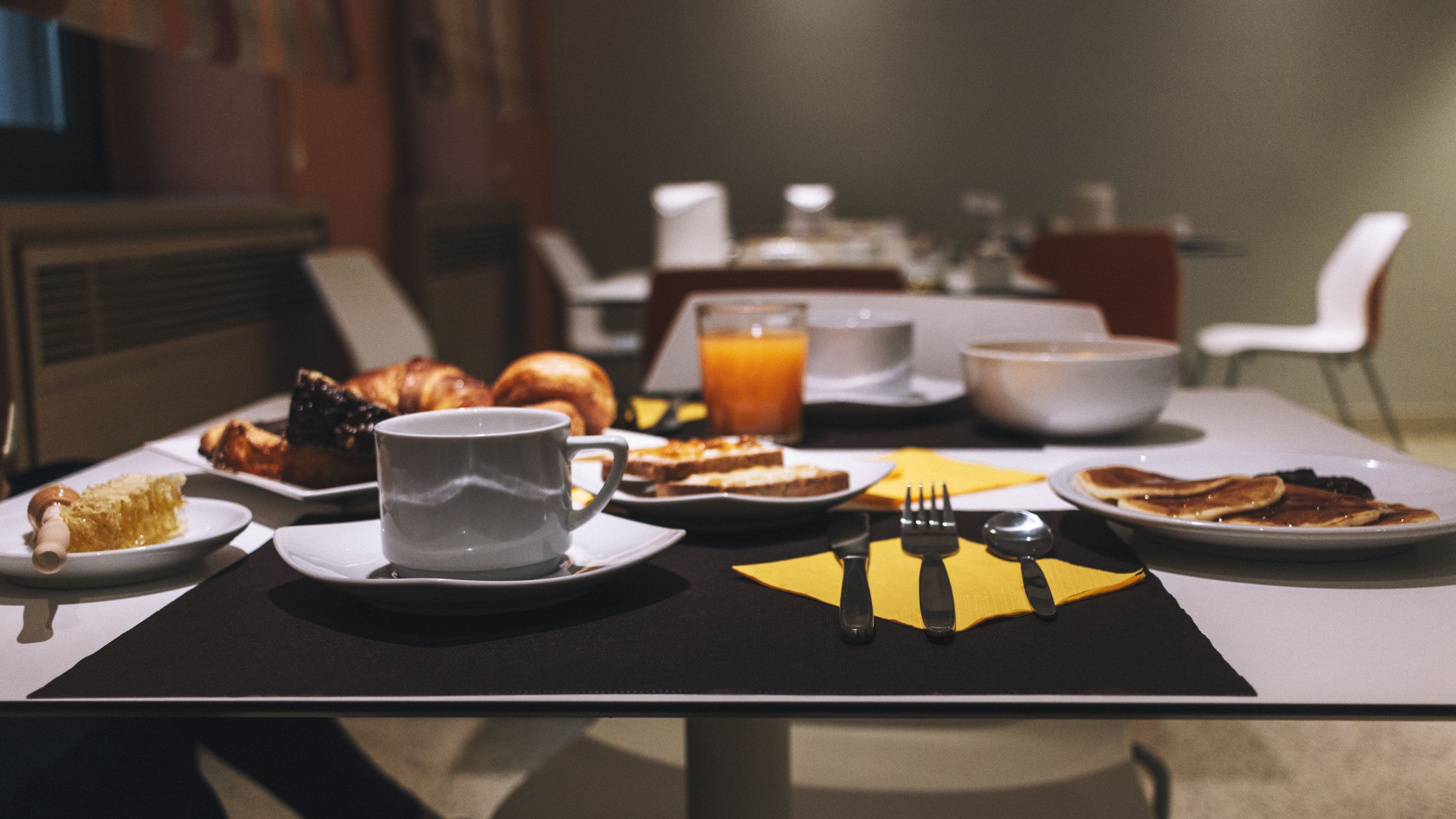 Une table de petit-déjeuner avec des assiettes remplies de nourriture, une tasse et des couverts.