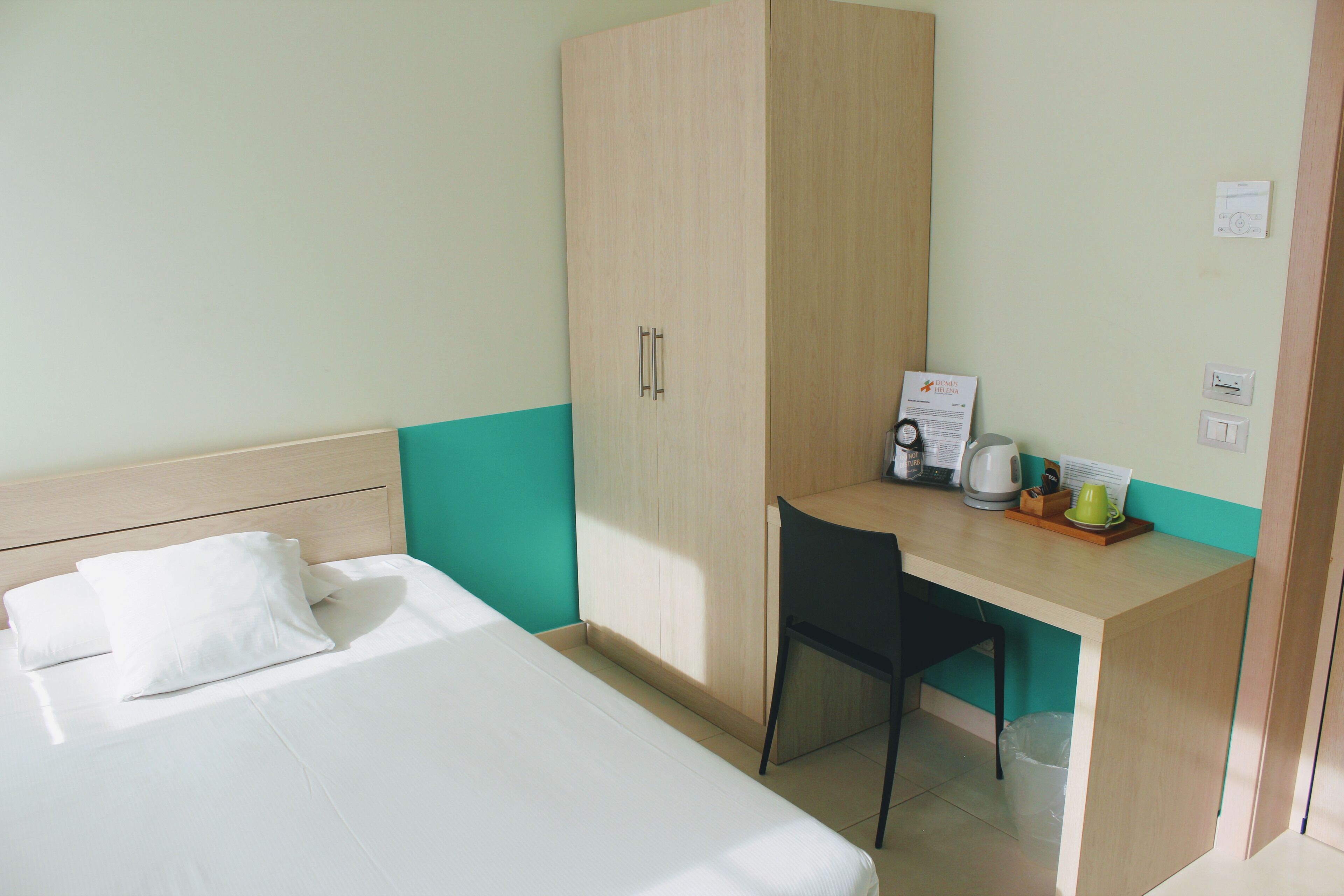Ein Hotelzimmer mit Bett, Schreibtisch, Stuhl und Kleiderschrank.