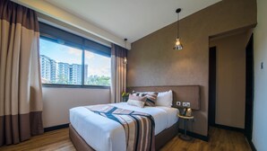 Ett modernt hotellrum med en stor säng, ett nattduksbord med en lampa och utsikt över stadsbilden genom fönstret.