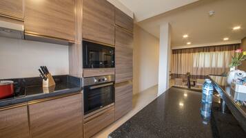 A modern kitchen with wooden cabinets, a black countertop, and a stainless steel oven.
