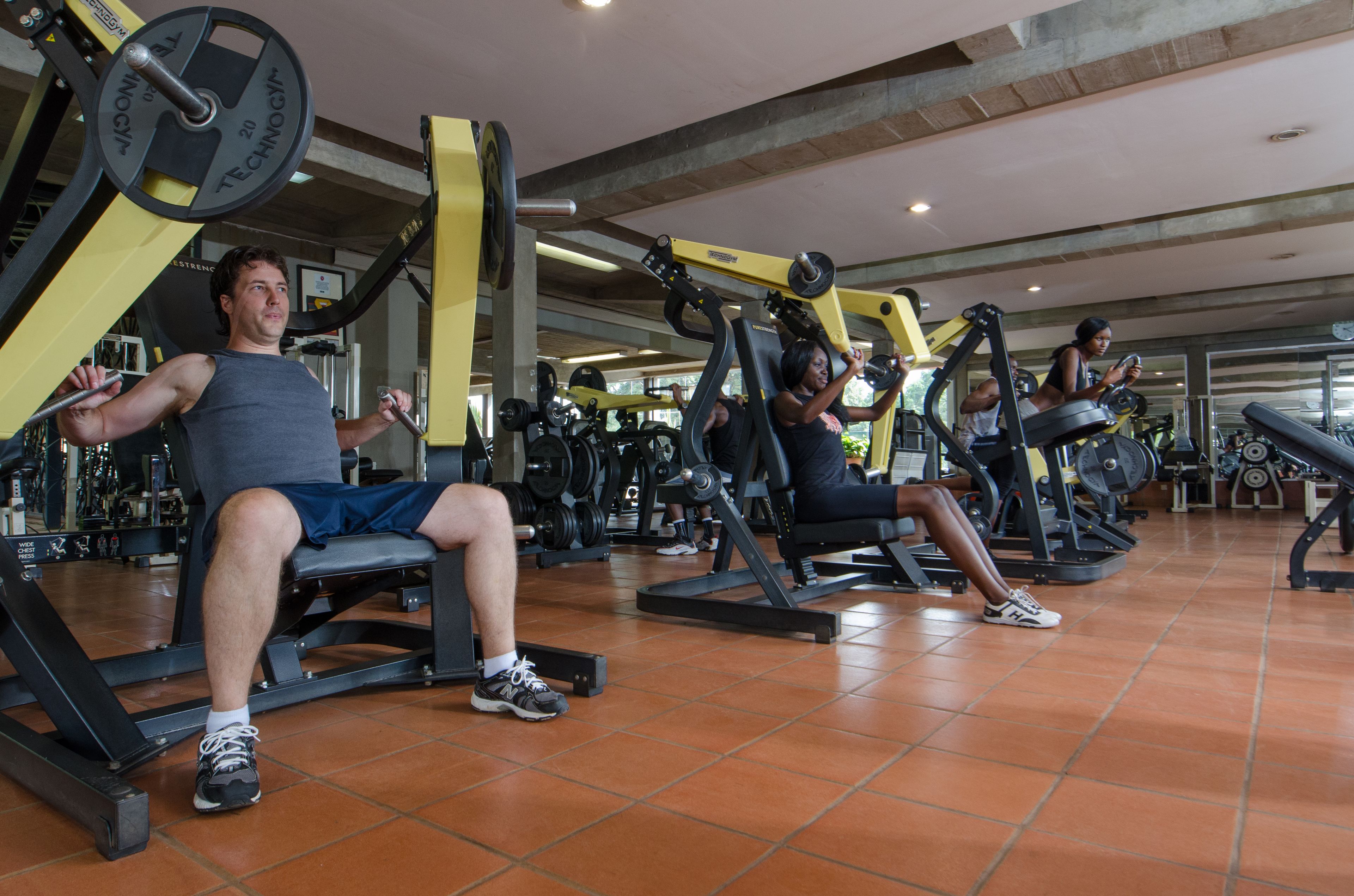 Ein Fitnessraum mit unterschiedlichen Trainingsgeräten und gefliestem Boden.