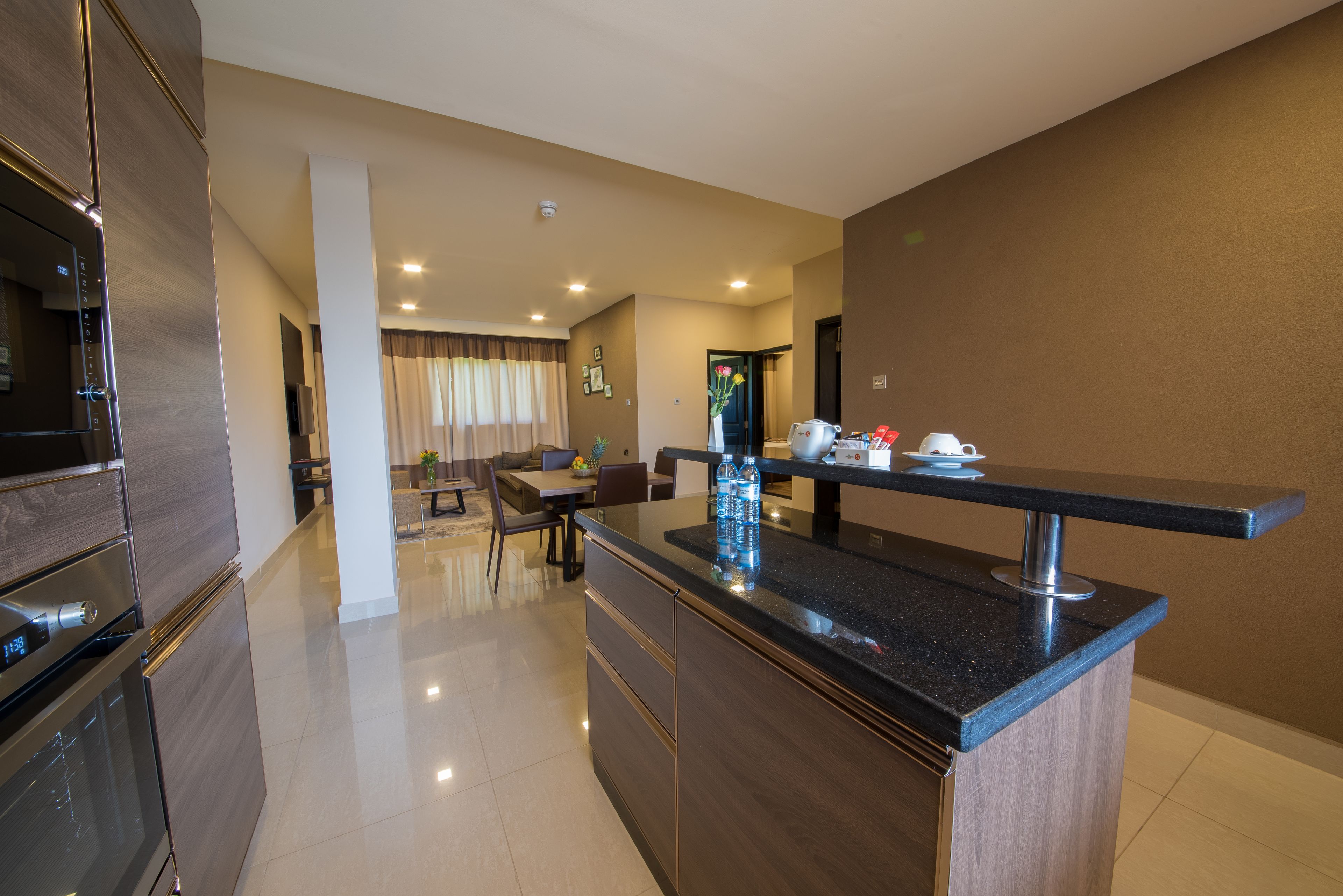 A modern kitchen with a built-in oven, a dining area with a table and chairs, and a living room with a sofa and a coffee table.