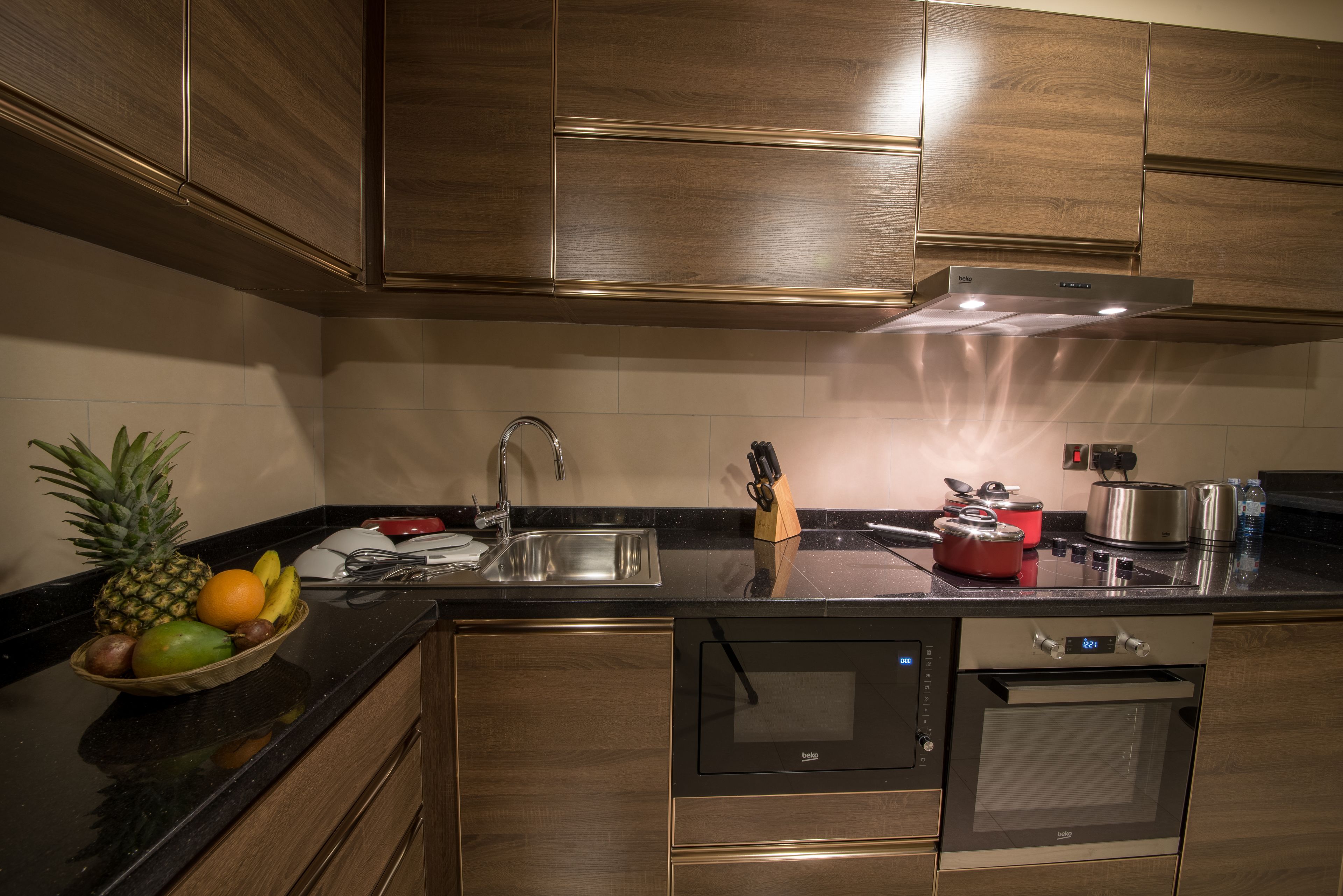 A modern kitchen with wooden cabinets, stainless steel appliances, and a fruit bowl on the counter.