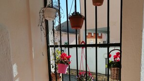 A balcony with a view of a cobblestone street, potted plants, and a stone wall. - Aria di Vacanza- Molara (Loiri Porto San Paolo)