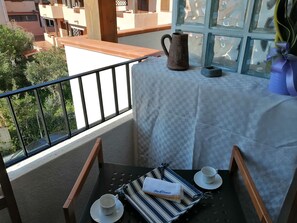 A balcony with a table set for two, a pitcher, and a decorative item. - Aria di Vacanza- Molara (Loiri Porto San Paolo)
