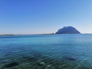 A clear view of a calm sea with a distant rocky island and a clear sky. - Aria di Vacanza- Molara (Loiri Porto San Paolo)