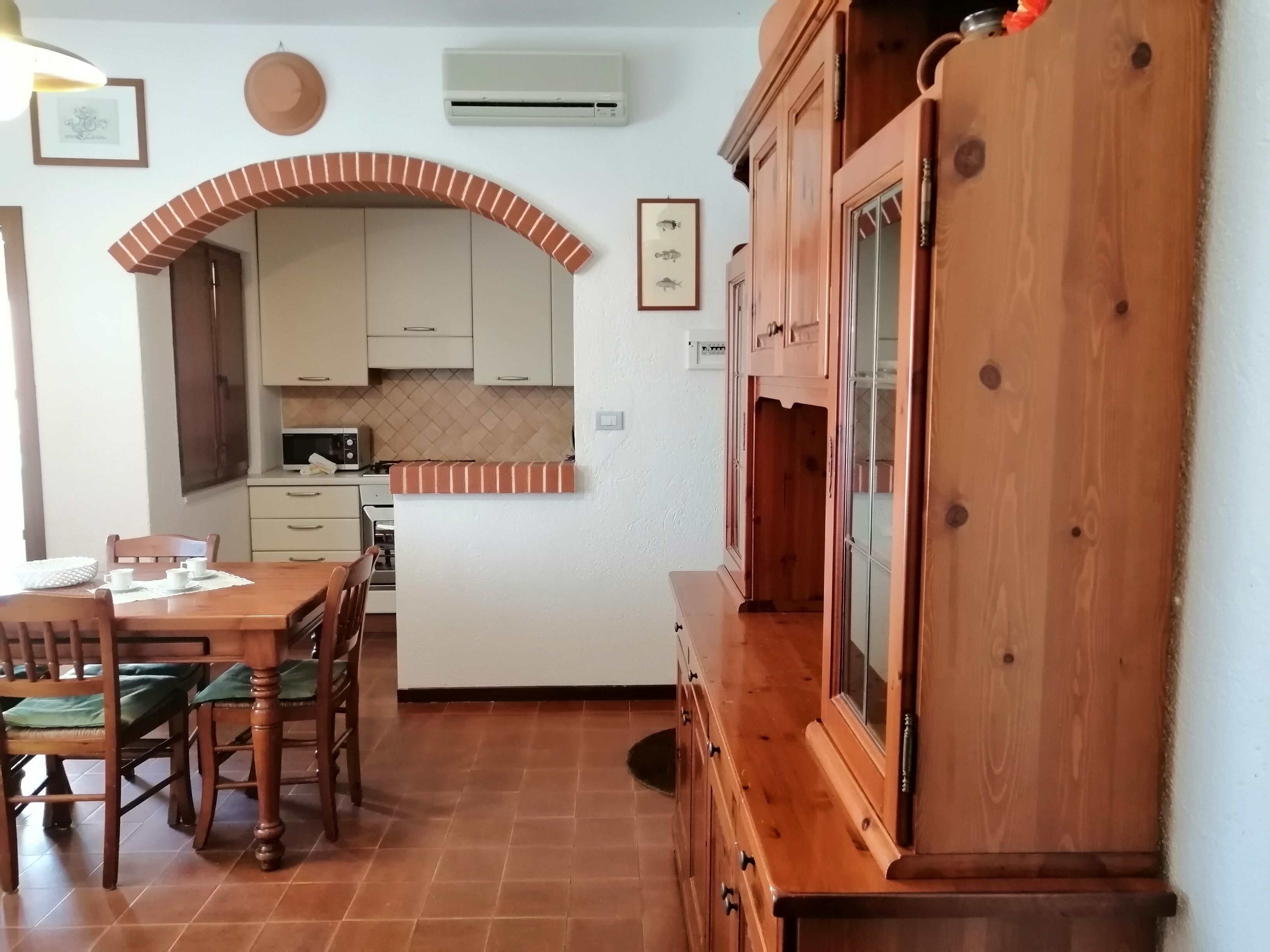 A kitchen with white cabinets, a microwave, and a wooden dining table with chairs.