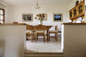 Un coin repas avec une table et des chaises en bois, un vase rempli de fleurs et des tableaux encadrés accrochés au mur.