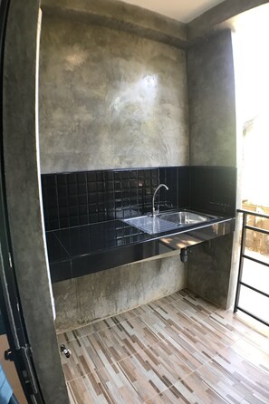 A kitchen with a black countertop, stainless steel sink, and tiled backsplash.