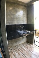 Una cocina con encimera negra, pileta de acero inoxidable y salpicadero de azulejos.