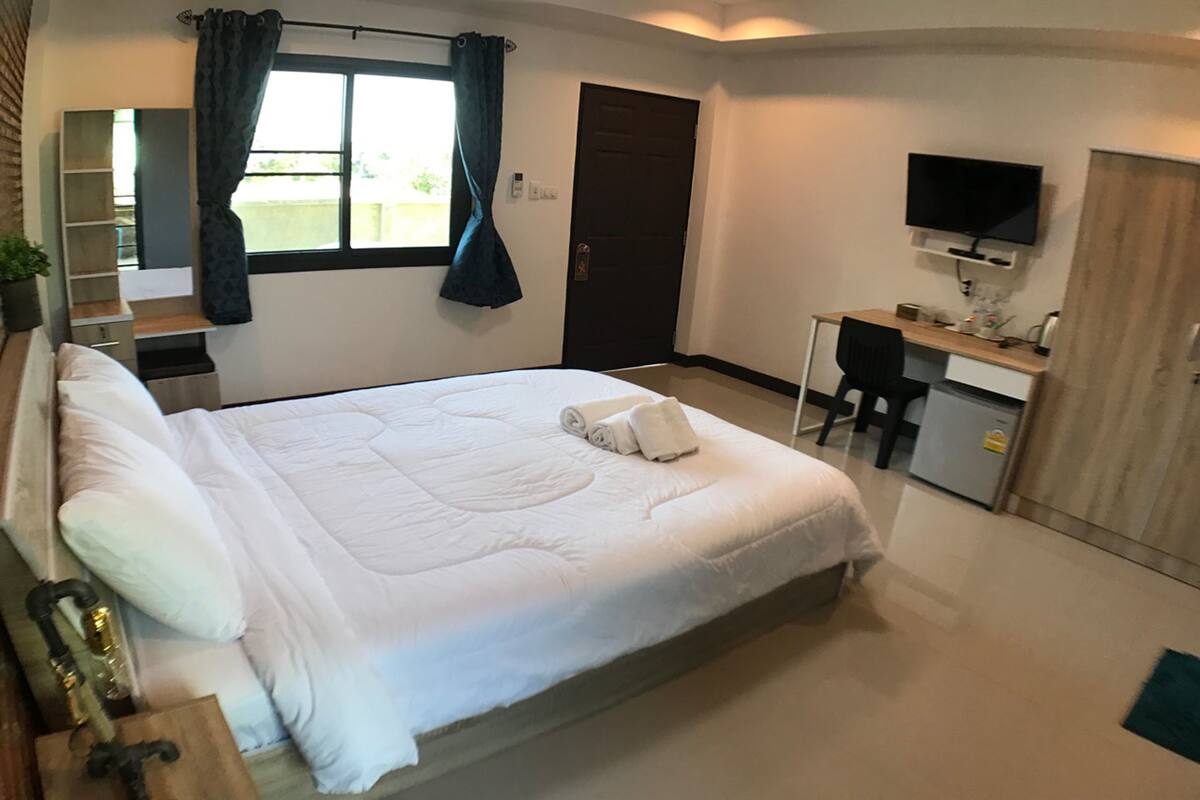 Un dormitorio con cama, escritorio, televisor y puerta.
