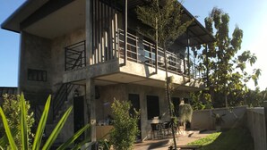 A two-story building with a balcony, outdoor seating, and a staircase. - Ban Roojai (Nan)