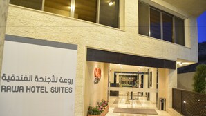 Exterior del Rawa Hotel Suites, con un letrero en árabe, una entrada moderna y una fachada bien iluminada.