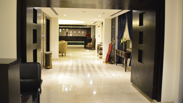 Un vestíbulo de hotel con mostrador de recepción, zona de estar y una pared decorativa.