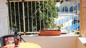 A balcony with a view of a blue building and trees.