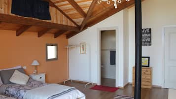 A bedroom with a wooden ceiling, a bed with a red rug, a nightstand, and a wall with a motivational quote.