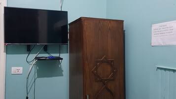 A room with a wooden cabinet, a television mounted on the wall, and a sign with instructions.