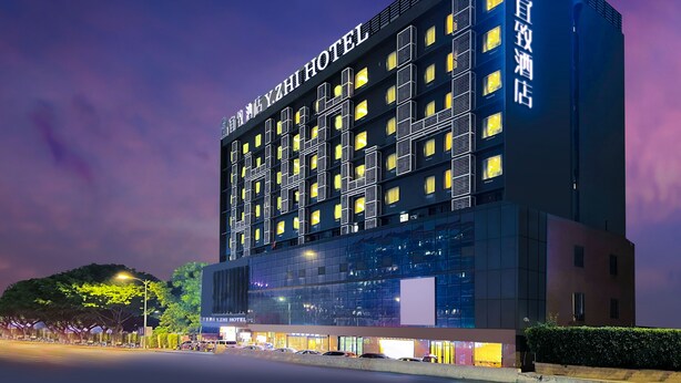A modern hotel building with multiple floors, large windows, and illuminated signage. - Yizhi flat (Guangzhou Zhujiang New Town Huashi Subway Station Branch) (Guangzhou)