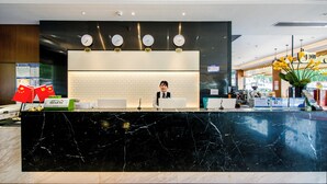 A hotel reception desk with a black marble counter, multiple clocks, and a receptionist. - Yizhi flat (Guangzhou Zhujiang New Town Huashi Subway Station Branch) (Guangzhou)