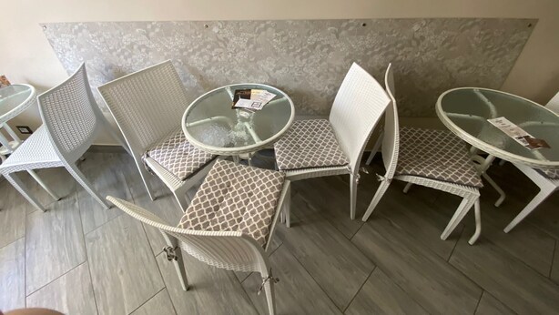 A seating area with white metal chairs and tables, a patterned cushion, and a textured wall. - B&B Cavirani (Gallipoli)