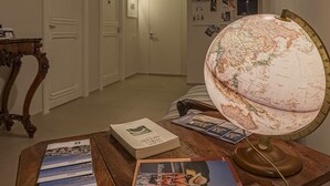 Uma sala de estudos com uma escrivaninha de madeira, um globo e diversos livros e revistas.