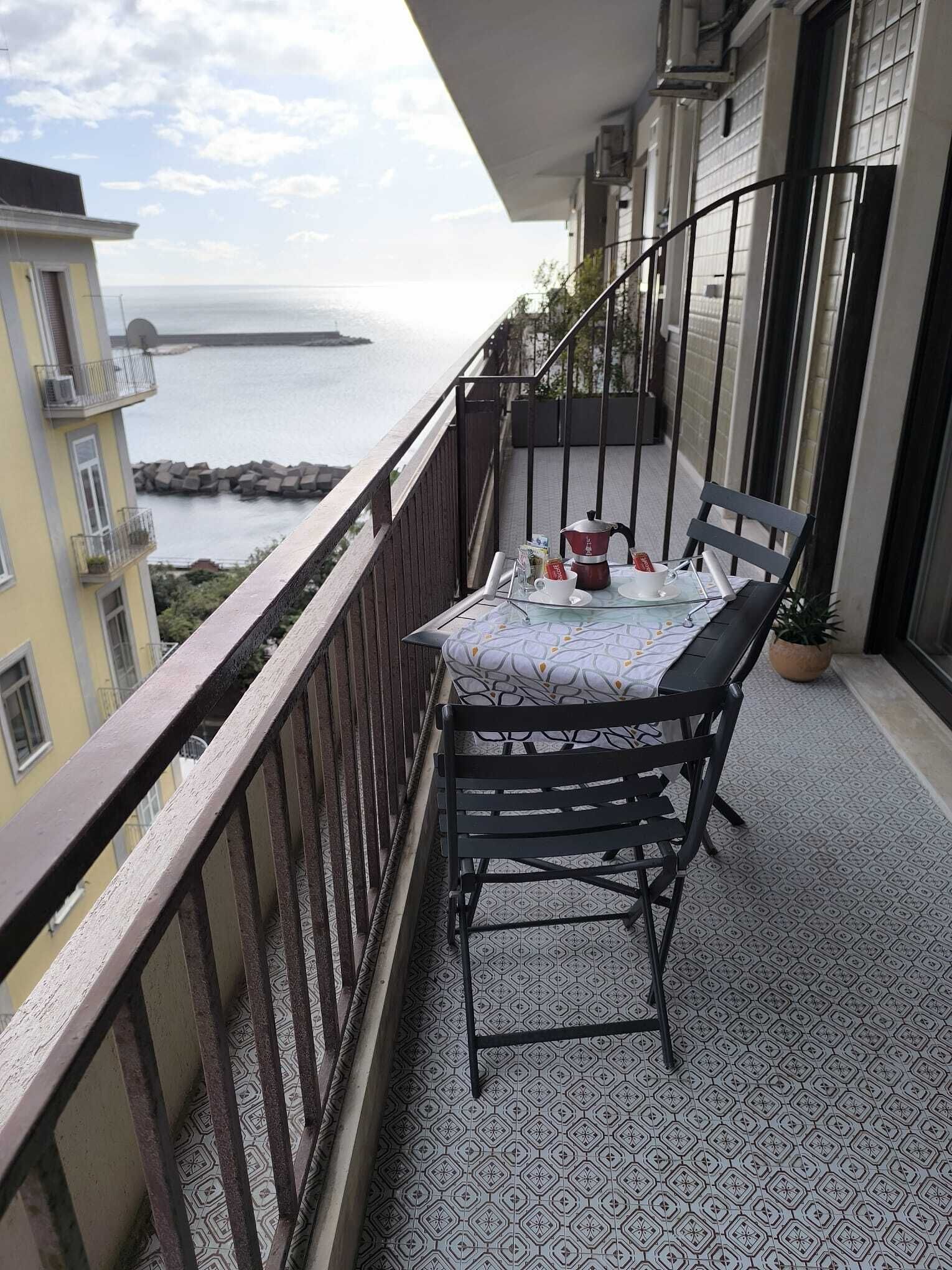 Un balcon avec une table dressée pour deux personnes, donnant sur une étendue d’eau.