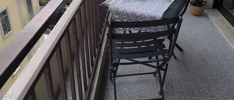 A balcony with a table set for two, overlooking a body of water.
