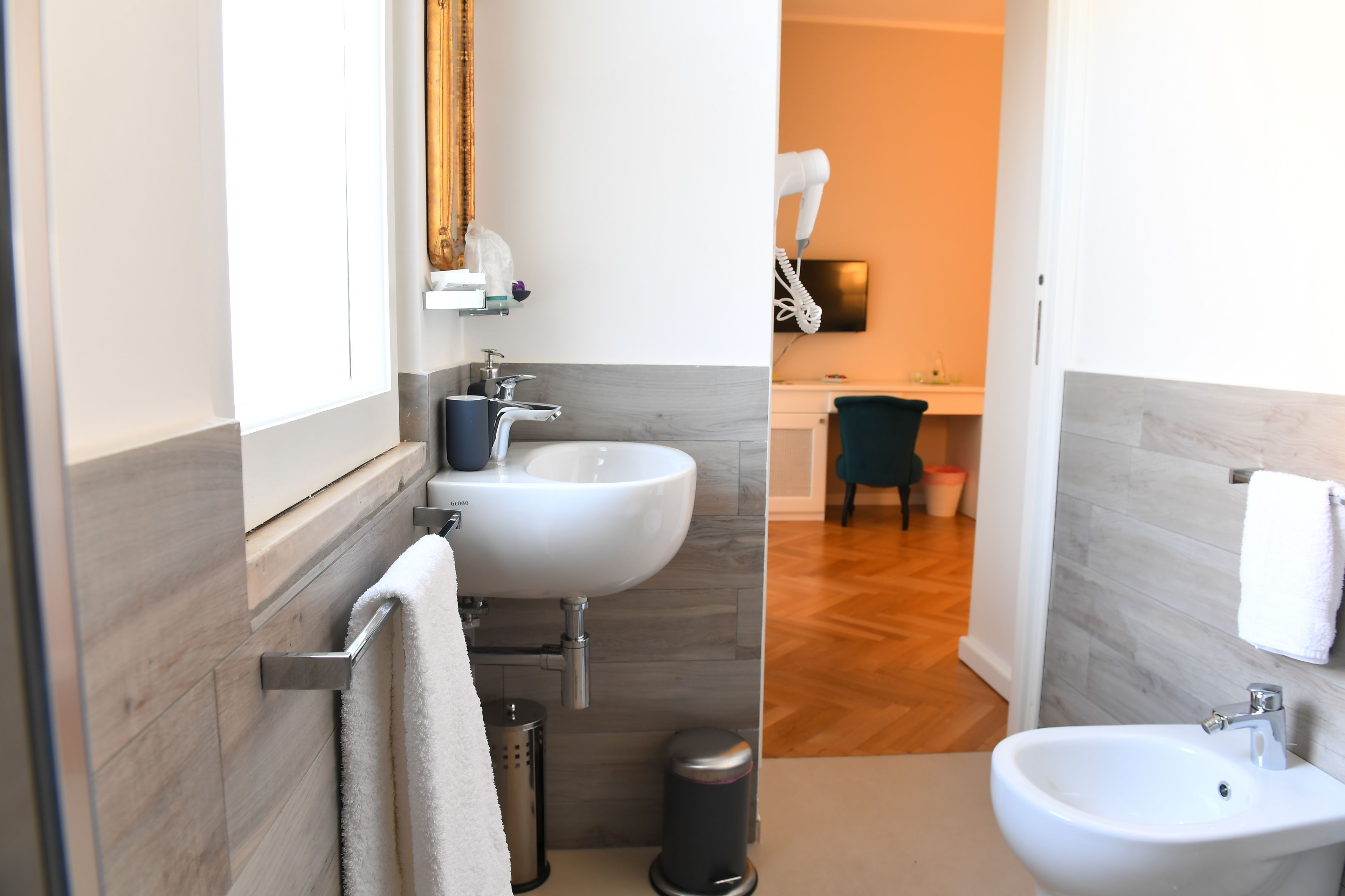 A modern bathroom with two sinks, a hairdryer, and a mirror.