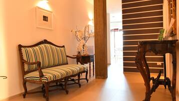 A hallway with a wooden bench, a small table with a vase, and a mirror on a stand.