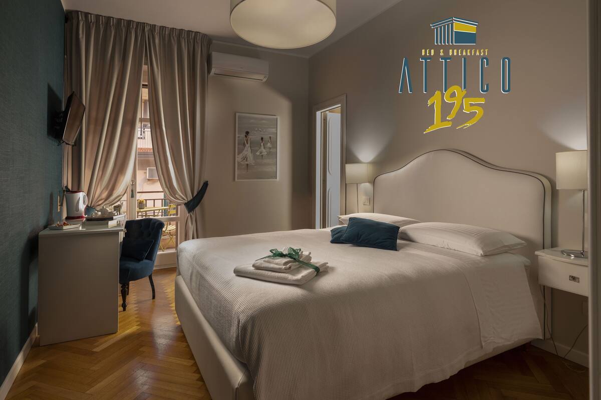 A modern bedroom with a large bed, bedside tables, a desk, and a chair.