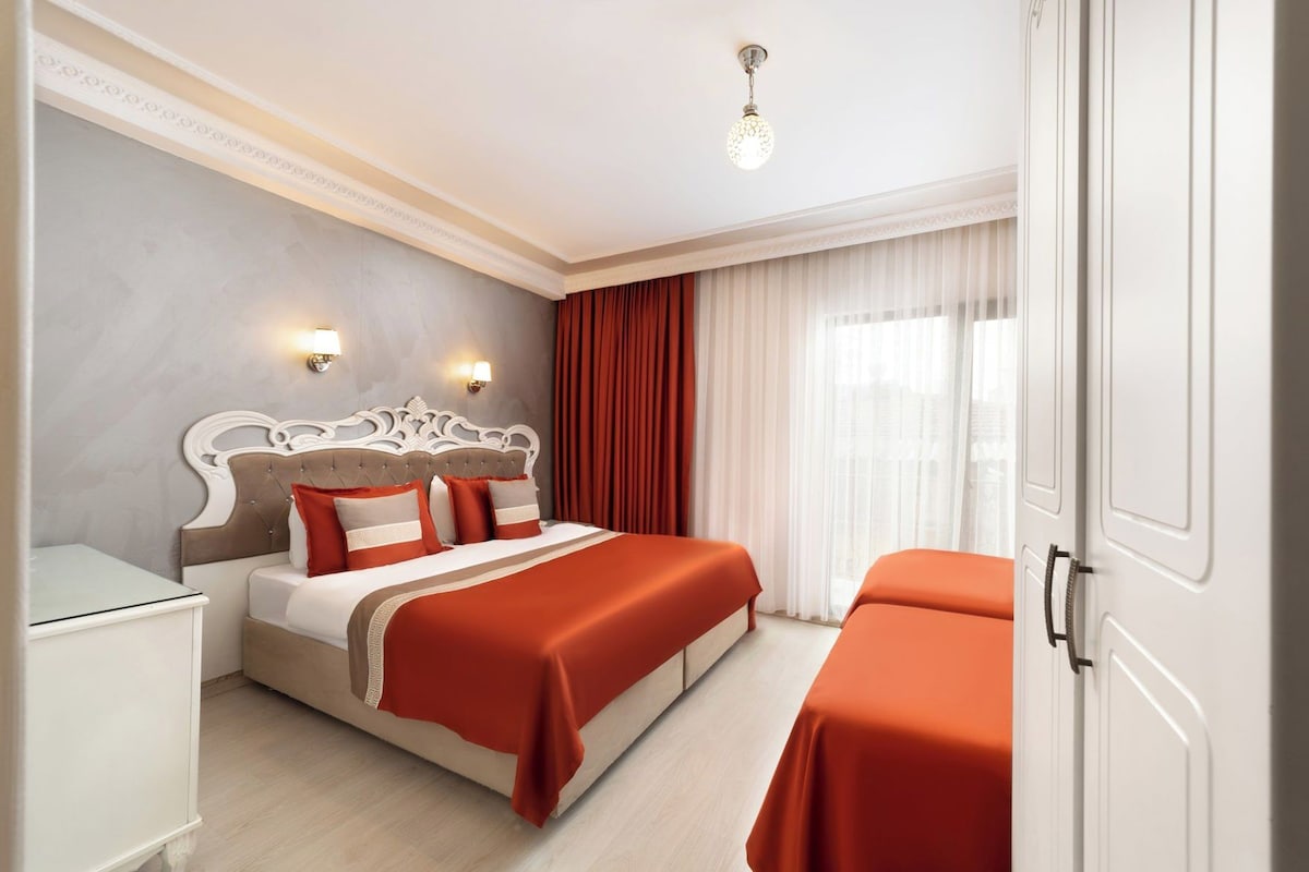 A hotel room with a bed, bedside tables, a wardrobe, and a window with curtains.