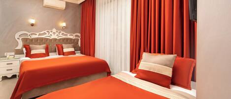 Habitación de hotel con dos camas, un espejo grande, un televisor de pantalla plana y una ventana con cortinas rojas.