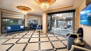 A lobby with a checkered floor, a blue sofa, a chandelier, and a view of the street outside. - Deluxe Newport Hotel - Old City (Istanbul)