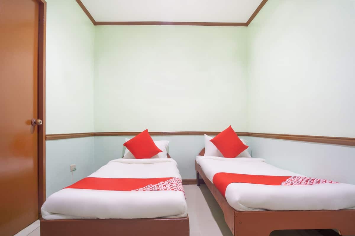 Une chambre avec deux lits simples, chacun recouvert d’une couvre-lit rouge et blanche et agrémenté d’oreillers assortis.