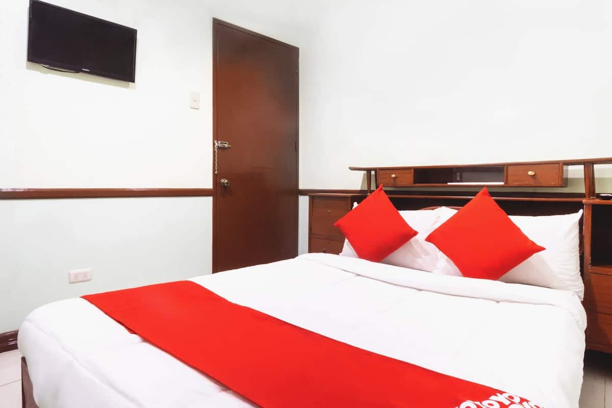 Une chambre d’hôtel avec un lit, un téléviseur fixé au mur, une armoire en bois et une porte.