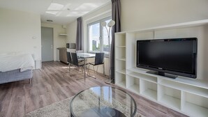 A modern living room with a flat-screen TV, a dining area with a glass table, and a kitchen in the background. - StudentStay (Leeuwarden)