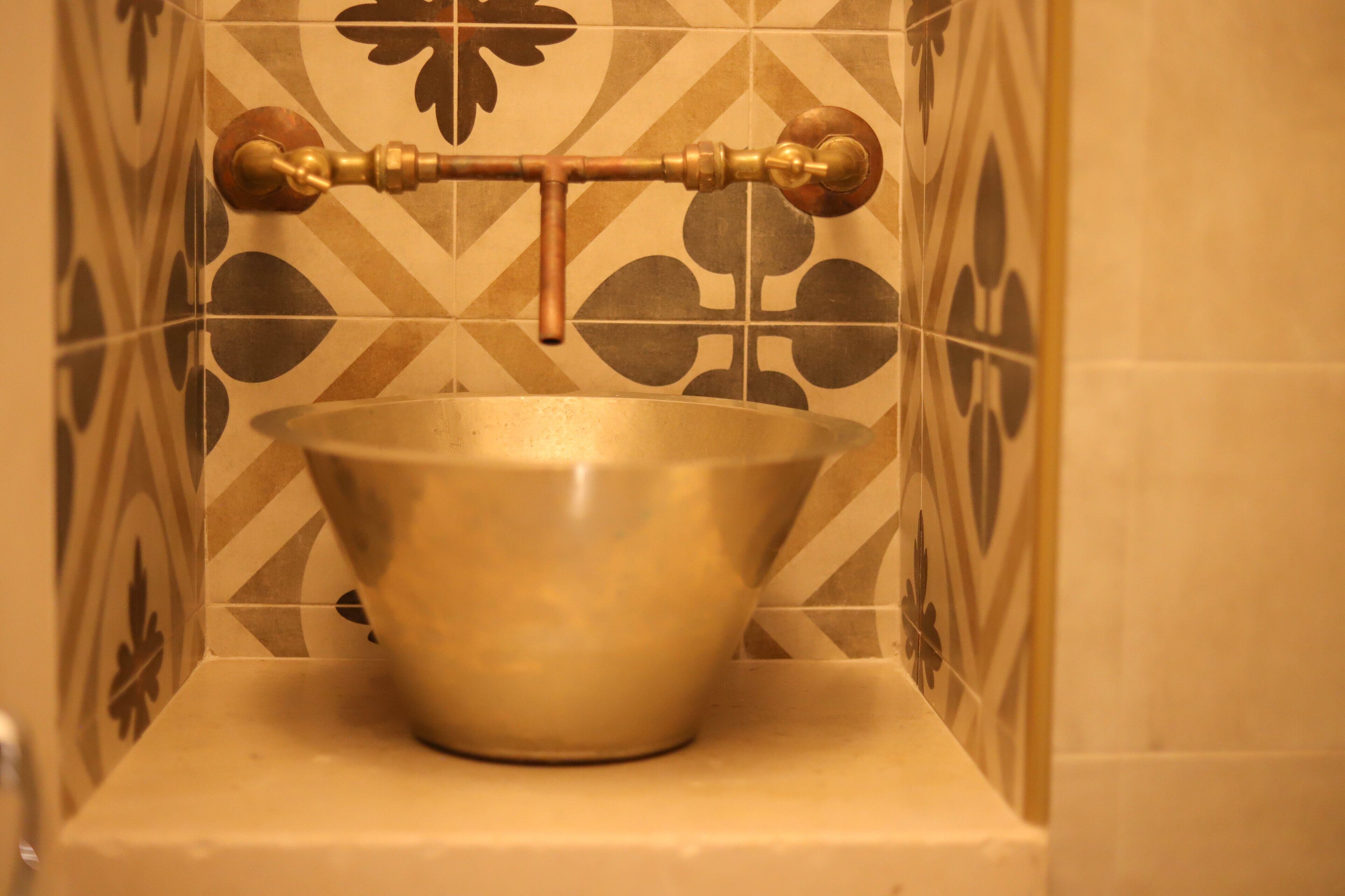 A bathroom with a brass faucet and a bowl sink.