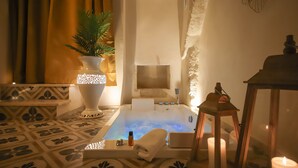 A spa room with a hot tub, a potted plant, candles, and a decorative lantern.