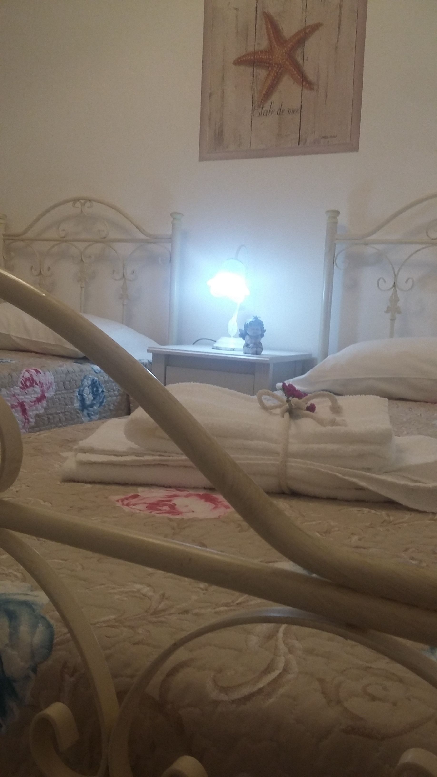 A bed with a decorative headboard, a bedside lamp, and a starfish decoration on the wall.