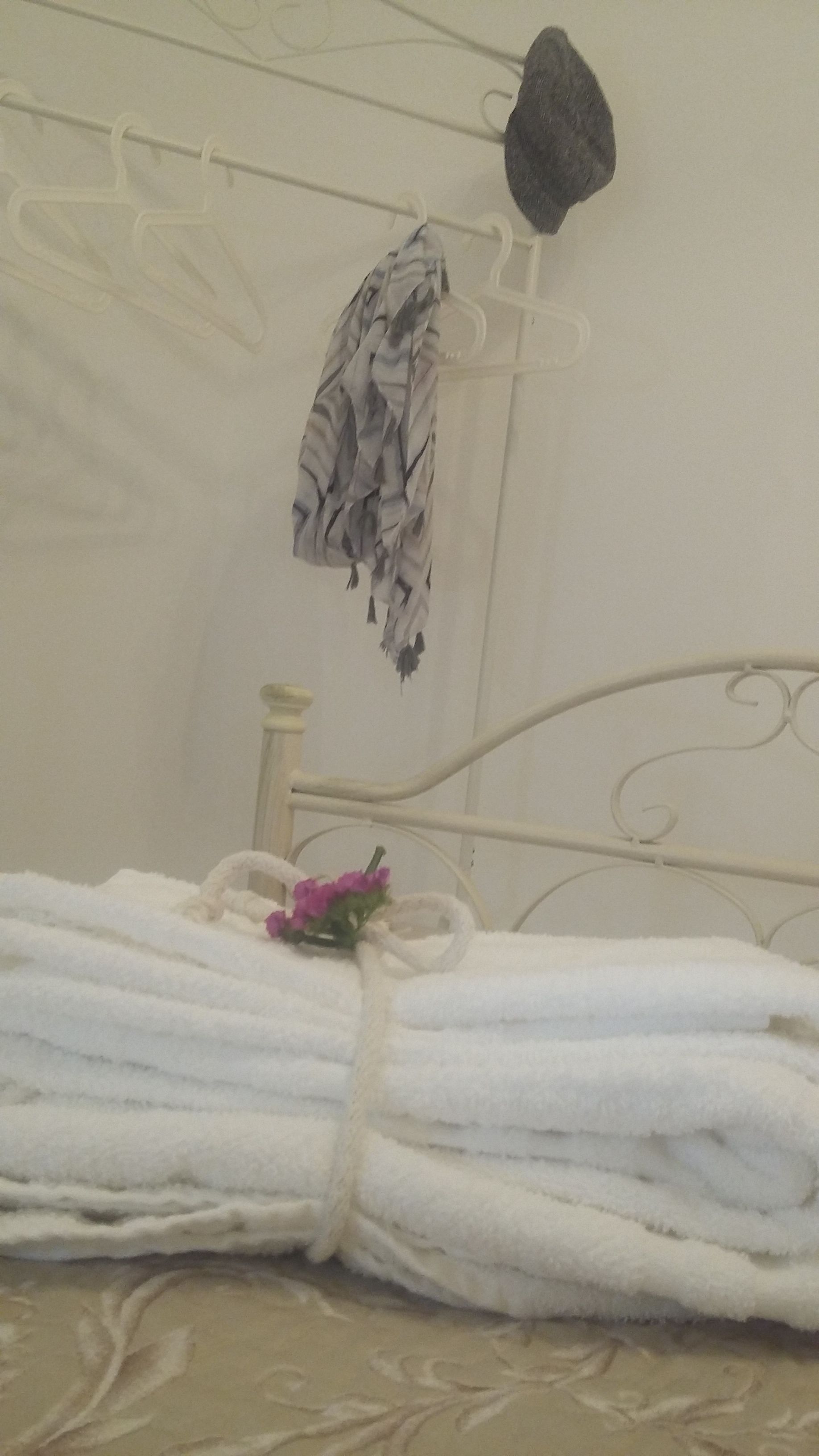 Een bed met witte handdoeken en een roze bloem.