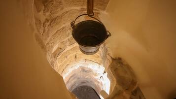 A narrow, arched stone passageway with a metal bucket hanging from the ceiling.